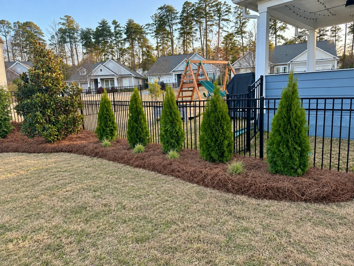 Closer view of a brick house with an oval mulched bed and poured curb