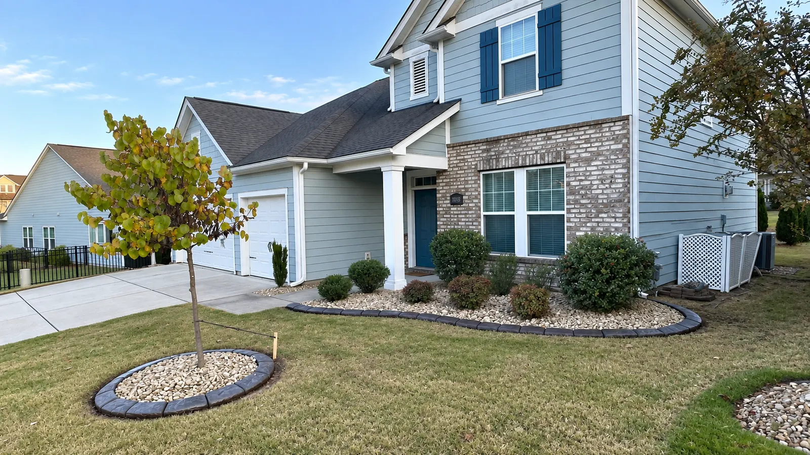 A finished front yard with a river-rock bed, a tree ring and a poured curb