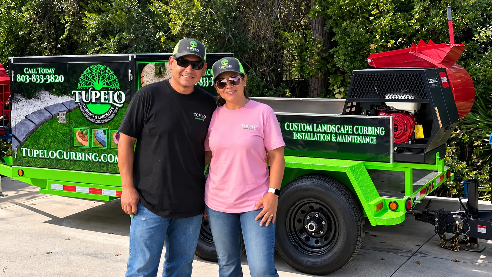 Jose and Holly Cedillo standing in front of their Tupelo Curbing and Landscape trailer